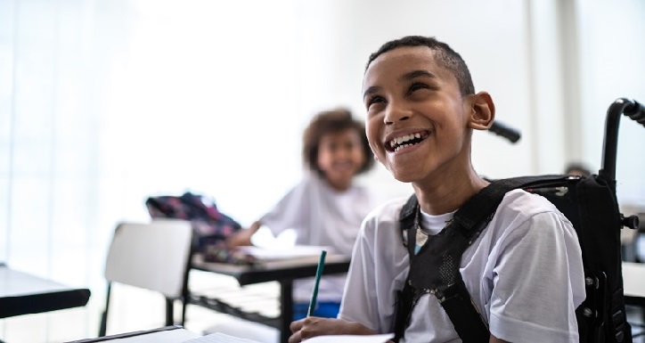 Child in a wheelchair smiling at the camera